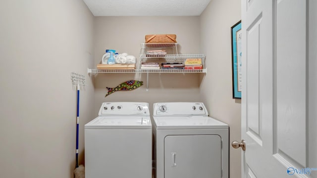 laundry room featuring a textured ceiling, laundry area, and washer and clothes dryer