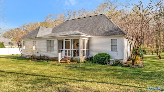 back of house featuring a shingled roof, fence, a yard, and a sunroom