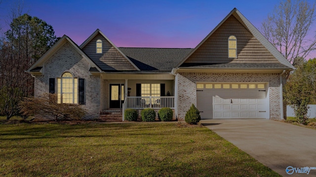 view of front of house featuring covered porch, concrete driveway, a garage, a lawn, and brick siding