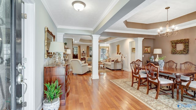 dining room with decorative columns, light wood-style floors, and ornamental molding