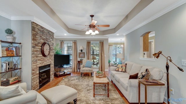 living area featuring a raised ceiling, a healthy amount of sunlight, wood finished floors, and ceiling fan