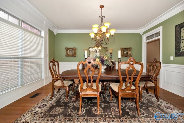 dining area with hardwood / wood-style floors, crown molding, and a notable chandelier