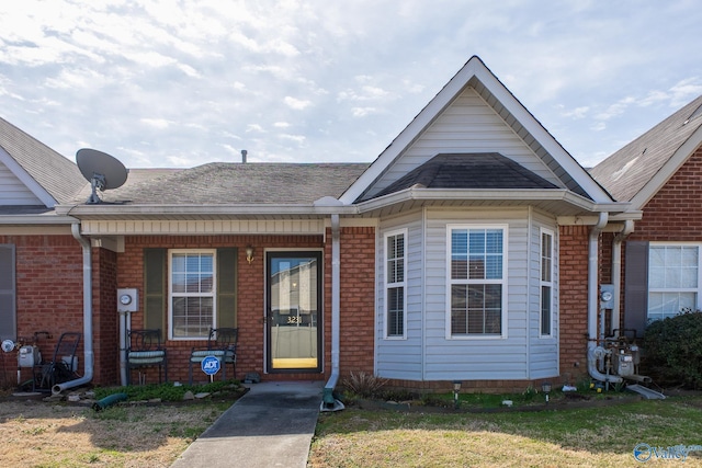 view of front facade featuring a shingled roof and brick siding