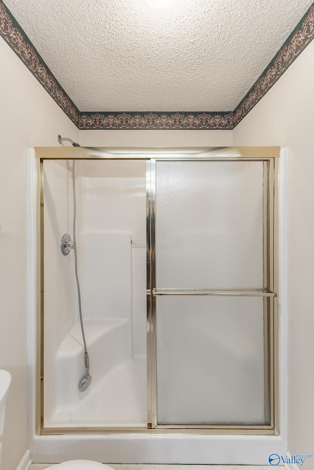 full bathroom with a stall shower and a textured ceiling