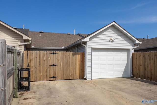 garage with concrete driveway and fence