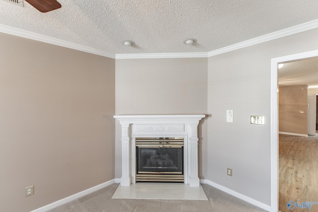 unfurnished living room with a fireplace with flush hearth, ornamental molding, ceiling fan, a textured ceiling, and baseboards