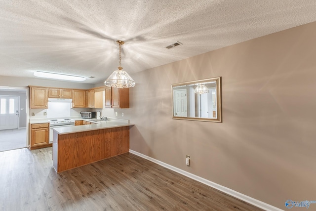 kitchen with white electric range, a peninsula, wood finished floors, visible vents, and light countertops