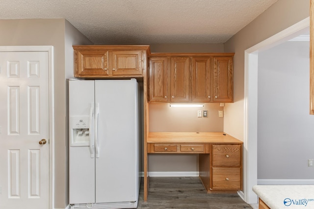 kitchen featuring dark wood-style floors, white refrigerator with ice dispenser, light countertops, and built in study area