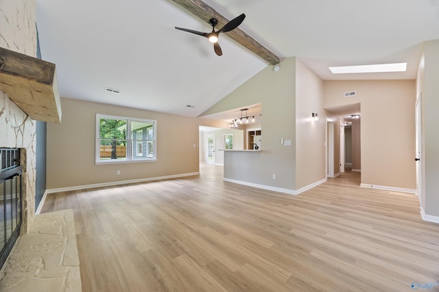 12034 Runningmeade Trl SE, Huntsville, AL 35803 - unfurnished living room featuring a stone fireplace, beamed ceiling, ceiling fan, light wood-type flooring, and a skylight