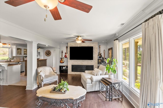 living room featuring a fireplace, wood-type flooring, ornamental molding, and ceiling fan