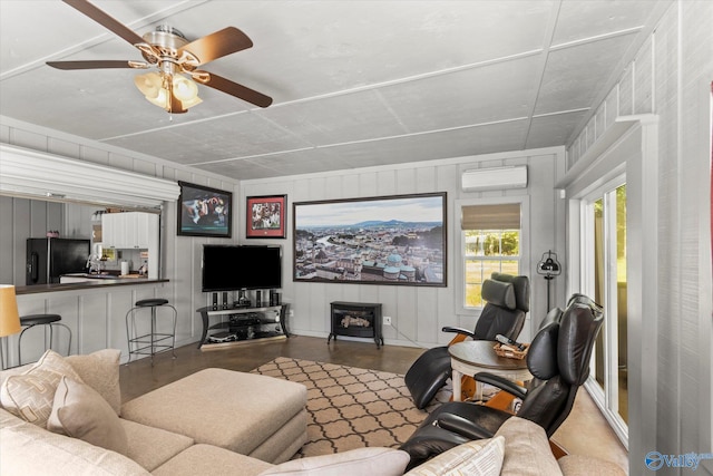 living room with a wall mounted AC, a wood stove, concrete flooring, and ceiling fan