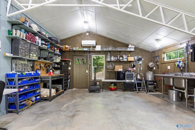 garage featuring an AC wall unit, wooden walls, and a workshop area