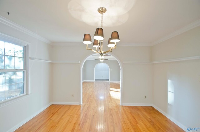 unfurnished dining area featuring wood-type flooring, ornamental molding, and ceiling fan with notable chandelier