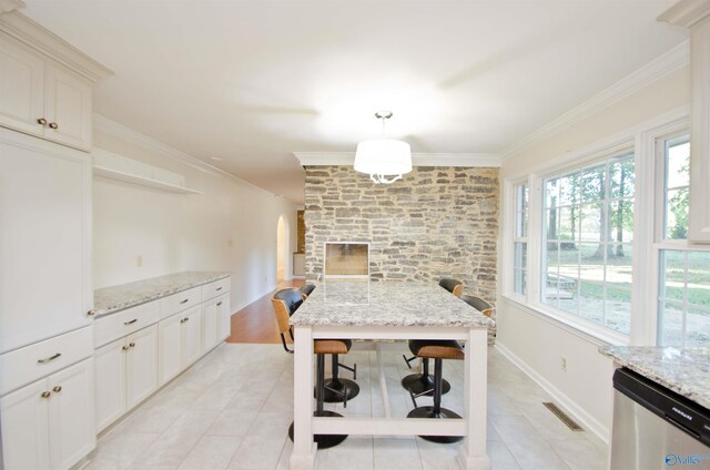 kitchen with ornamental molding, stainless steel dishwasher, light stone counters, and decorative light fixtures