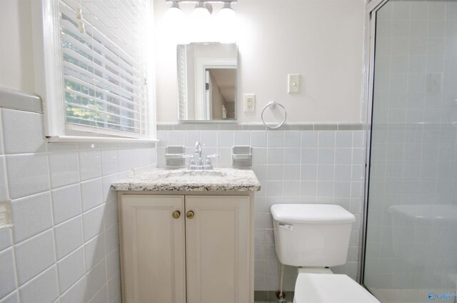 bathroom featuring tile walls, vanity, a shower with shower door, and toilet