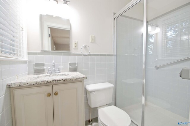 bathroom featuring vanity, toilet, tile walls, and an enclosed shower