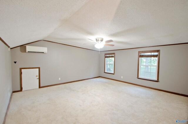 spare room featuring an AC wall unit, a textured ceiling, and light colored carpet