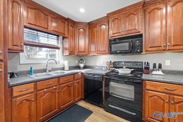 kitchen featuring dark countertops, brown cabinets, a sink, and black appliances