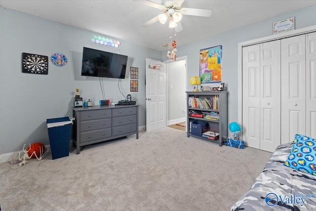 interior space with light carpet, baseboards, ceiling fan, a textured ceiling, and a closet