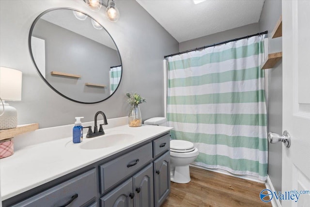 full bathroom with a textured ceiling, vanity, toilet, and wood finished floors