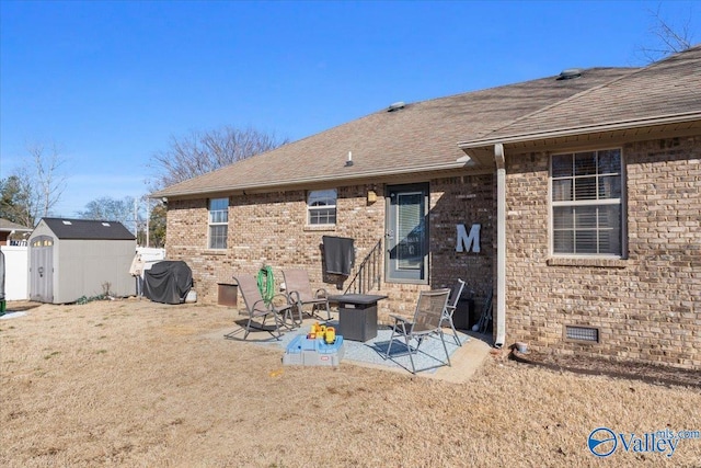 back of property with crawl space, an outdoor structure, a patio area, a shed, and brick siding