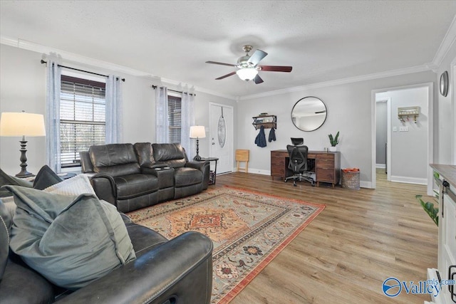 living area featuring a ceiling fan, light wood-type flooring, crown molding, and baseboards