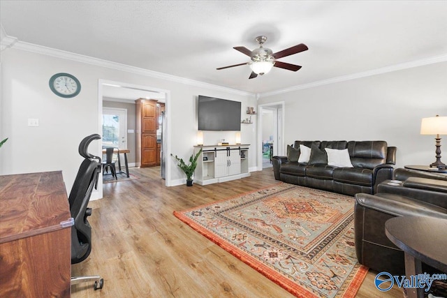 living room featuring light wood finished floors, ornamental molding, and a ceiling fan