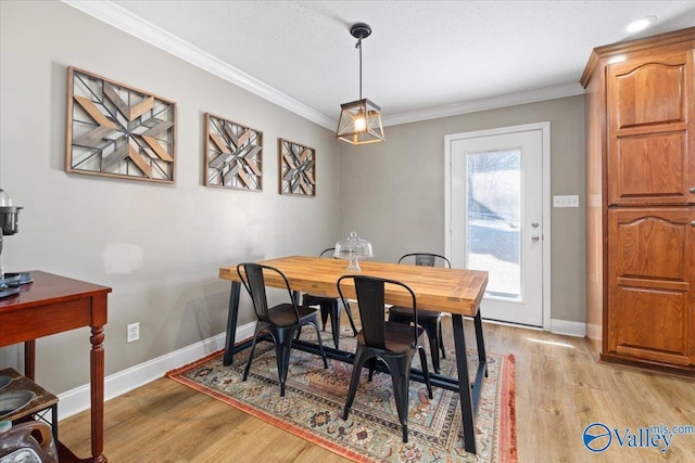 dining area featuring light wood-type flooring, baseboards, ornamental molding, and a textured ceiling