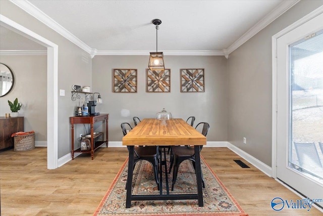 dining area with ornamental molding, light wood finished floors, visible vents, and baseboards