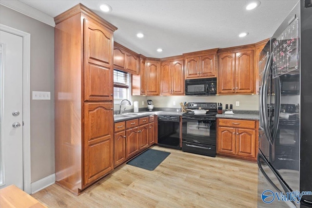 kitchen featuring black appliances, brown cabinetry, dark countertops, and a sink