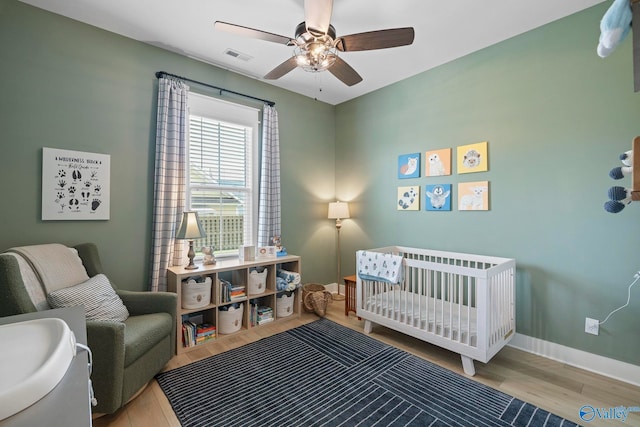 6320 Loring Loop NW, Huntsville, AL 35806 - bedroom featuring a nursery area, wood finished floors, and a ceiling fan