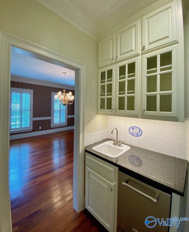 kitchen with dark hardwood / wood-style floors, sink, backsplash, crown molding, and an inviting chandelier