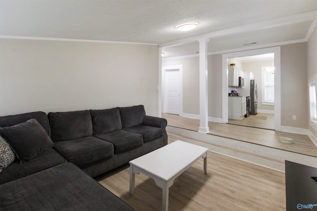 living room featuring light hardwood / wood-style flooring, a textured ceiling, and ornamental molding