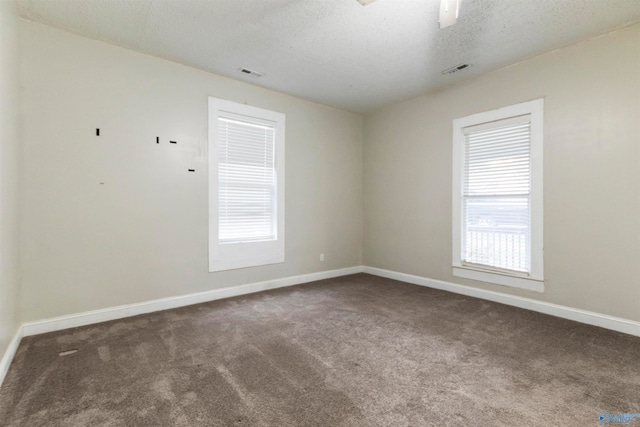 spare room featuring dark colored carpet and a textured ceiling