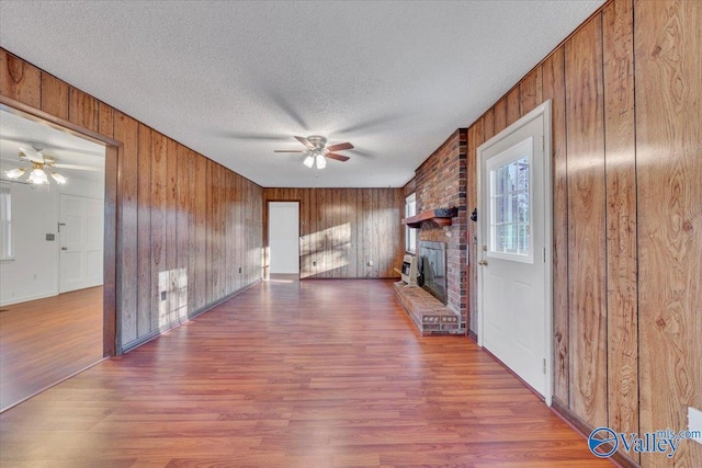 unfurnished living room with a fireplace, ceiling fan, and wood finished floors