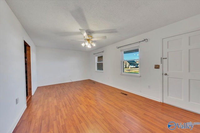 unfurnished room with light wood-type flooring, visible vents, a textured ceiling, and a ceiling fan