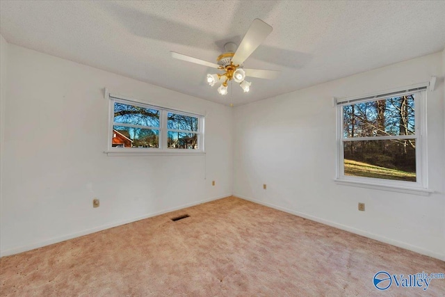 unfurnished room featuring visible vents, a textured ceiling, carpet, baseboards, and ceiling fan