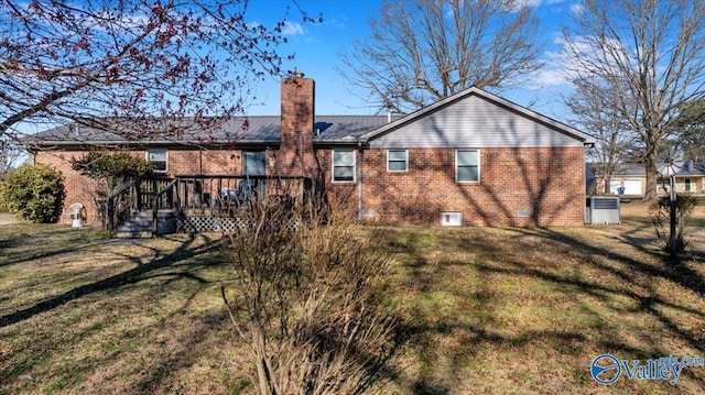 rear view of house with a yard, brick siding, and a chimney