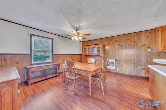 dining area featuring light wood-style flooring, heating unit, a wainscoted wall, and a textured ceiling