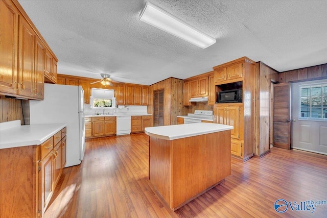 kitchen featuring white appliances, light countertops, light wood-style floors, and under cabinet range hood