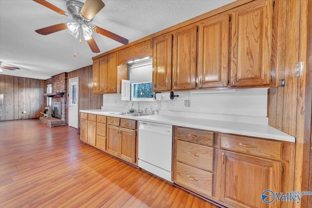 kitchen featuring a ceiling fan, brown cabinetry, a sink, light wood-style floors, and dishwasher