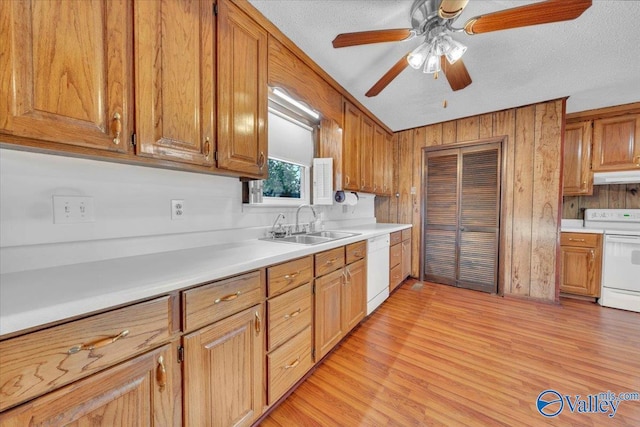 kitchen featuring white appliances, a sink, light countertops, under cabinet range hood, and light wood-type flooring