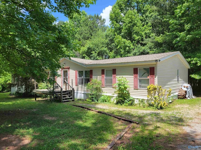 manufactured / mobile home featuring a front yard and roof with shingles