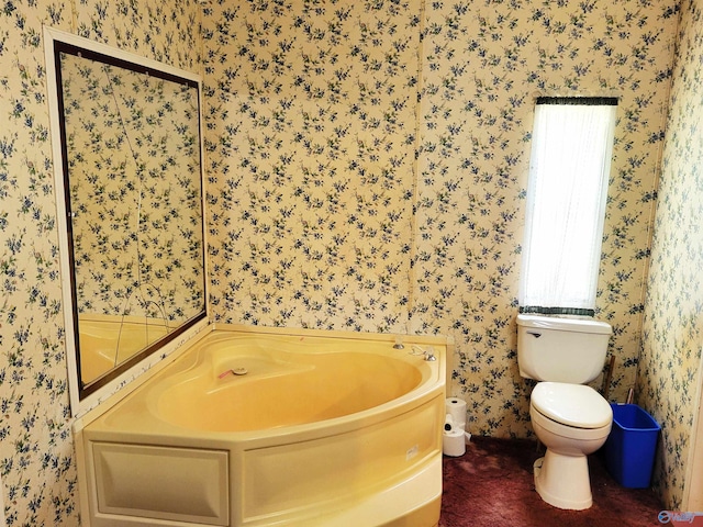 bathroom with toilet, a wealth of natural light, and a tub to relax in