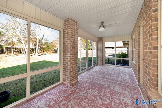 unfurnished sunroom featuring a wealth of natural light, ceiling fan, and wooden ceiling