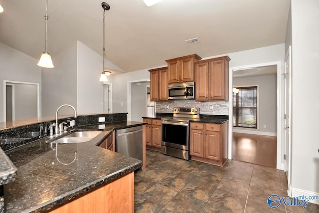 kitchen featuring appliances with stainless steel finishes, sink, dark stone countertops, dark hardwood / wood-style floors, and hanging light fixtures