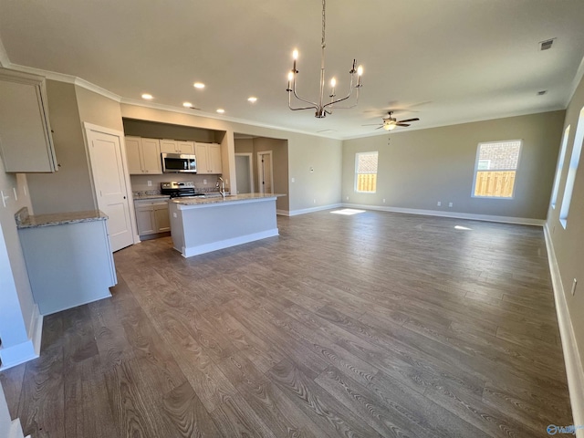 kitchen with dark wood finished floors, crown molding, a center island with sink, appliances with stainless steel finishes, and a sink