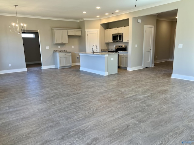 kitchen featuring a center island with sink, baseboards, appliances with stainless steel finishes, open floor plan, and ornamental molding