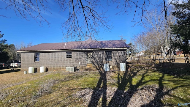 rear view of house with cooling unit and a lawn