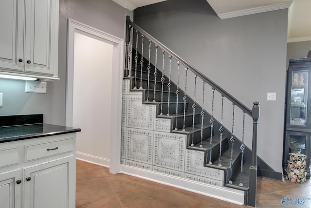 staircase with crown molding and tile patterned floors